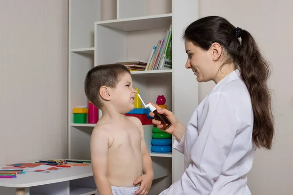 Een kinderarts en een jongen van 3-4 jaar oud. Neusspray, behandeling met rhinitis, loopneus. — Stockfoto