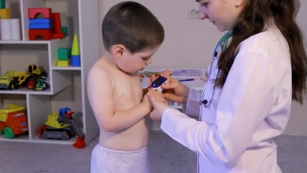 Barnläkaren mäter barnens syrehalt i blodet med en pulsoximeter. Lunginflammation och koronavirus hos barn — Stockvideo