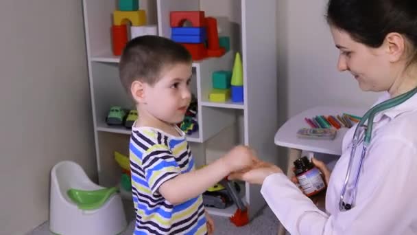 Una pediatra o infermiera donna dà a un bambino una pillola vitaminica bianca. Integratori alimentari per bambini, vitamine. — Video Stock