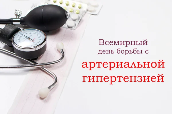 Lékařská fotografie s tonometrem, tabletami a fonendoskopem s nápisem v ruštině, překlad: Světový den hypertenze — Stock fotografie
