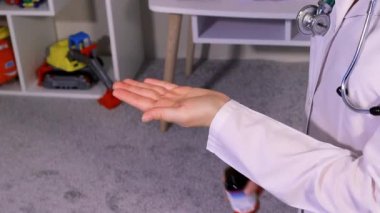 Beyaz üniformalı bir çocuk doktoru ya da hemşire kavanozdan D vitamini döker. Çocuklar için biyokatkı maddeleri.