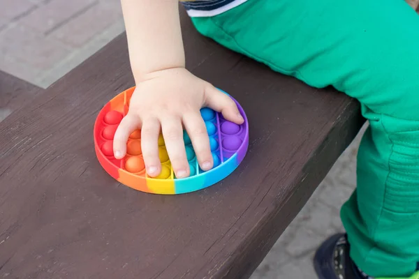 Juguete antiestrés multicolor Pop it y un niño pequeño primer plano. — Foto de Stock
