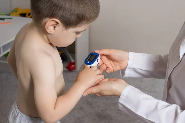 Педиатр измеряет уровень кислорода в крови детей с помощью пульсоксиметра. Пневмония и коронавирус у детей — стоковое фото