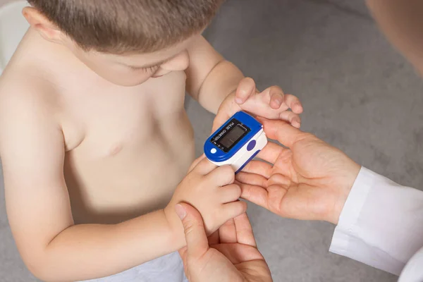 O pediatra mede o nível de oxigênio no sangue das crianças com um oxímetro de pulso. Pneumonia e coronavírus em crianças — Fotografia de Stock