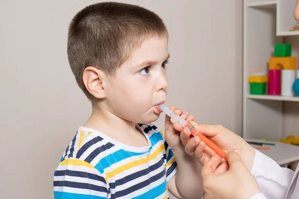 The pediatrician or nurse gives the child syrup in a measuring syringe. Treatment of cough, temperature in children. Paracetamol or ibuprofen for toddlers and preschoolers in pediatrics Royalty Free Stock Photos