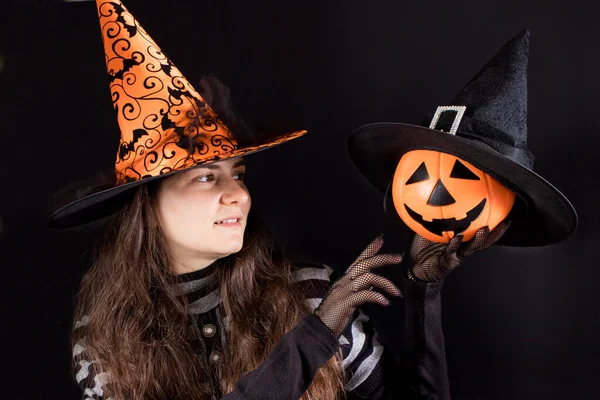 Egy narancs sapkás boszorkányjelmezes nő töklámpás emelőt tart. Emberek Halloween. — Stock Fotó