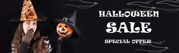 Halloween försäljning banner specialerbjudande. En kvinna i en häxdräkt håller en pumpa lykta jack och täcker sin mun med handen. — Stockfoto