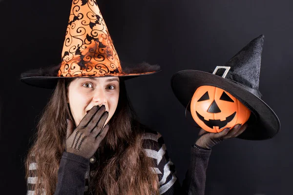 Una mujer con un disfraz de bruja sostiene un gato de linterna de calabaza y se cubre la boca con la mano. Venta de Halloween —  Fotos de Stock