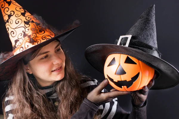 Una mujer con un disfraz de bruja con un sombrero naranja sostiene un gato de linterna de calabaza. Gente Halloween. —  Fotos de Stock