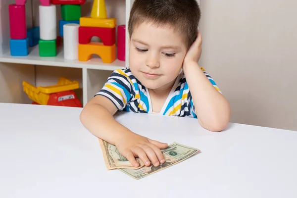Krásné dětské a dolarové bankovky. Chlapec přemýšlí, kam ty peníze utratit. Finanční gramotnost pro děti — Stock fotografie