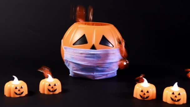 Coronavirus di Halloween. Zucca in una maschera su uno sfondo nero, caramelle versate in un secchio — Video Stock