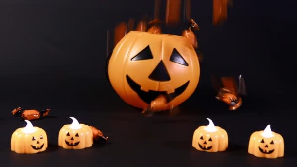 Oranžové halloweenské cukroví se nalévá do kbelíku dýně. Příprava na Halloween, černé pozadí. — Stock video