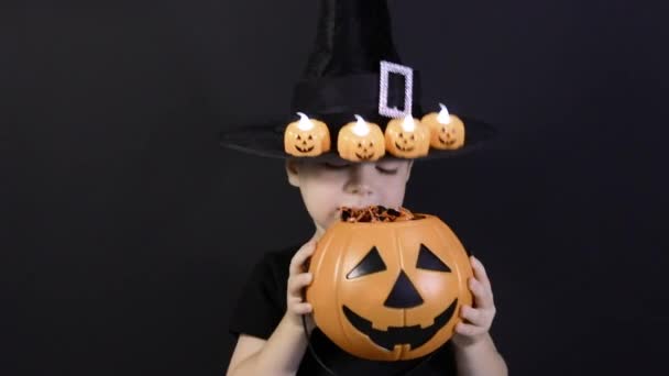 Egy halloweeni gyerek tart egy tököt cukorkával és sikoltozással, dalokat énekel. Felkészülés a nyaralásra — Stock videók