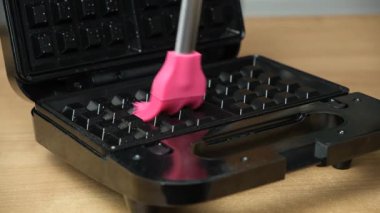 Waffle ızgarasının yüzeyini yağlamak, ev yapımı waffle yapmaya hazırlanmak.