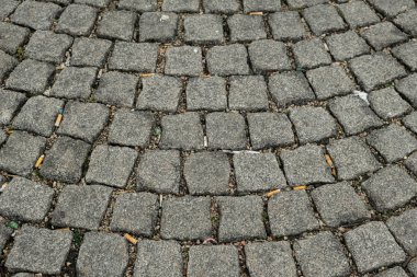 Kirli granit taş sokağın yakınında sigara atıkları var..