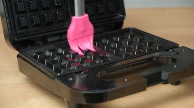 Waffle ızgarasının yüzeyini yağlamak, ev yapımı waffle yapmaya hazırlanmak.