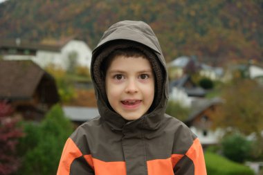 8 yaşındaki mutlu çocuk sonbahar parkında yürüyor, kameraya bakıyor..
