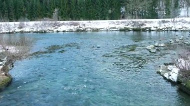 Kışın karlı bir vadide akan bir nehrin manzaralı yavaş çekimi.
