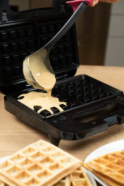 Siyah Elektrikli Waffle makinesine bir kepçeyle Taze Waffle Hamuru döküyorum