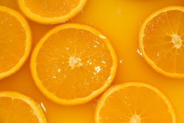 Portakal suyuna serpiştirilmiş taze portakal dilimleri. Meyvemsi parlak arkaplan.