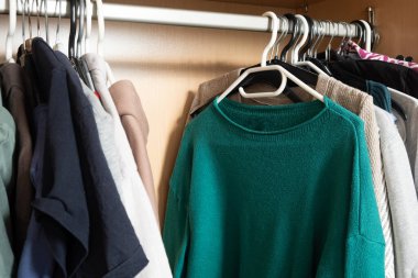 Minimalist örgü ve gömlek organizasyonu. Parlak dolaptaki askılar üzerinde..