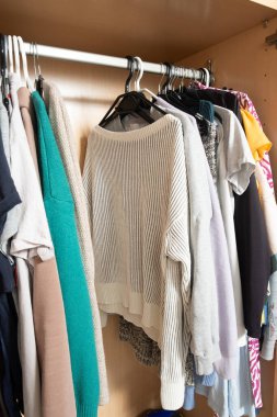 Minimalist örgü ve gömlek organizasyonu. Parlak dolaptaki askılar üzerinde..