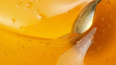Kaşık ile karıştırılmış sıvı bal, hava kabarcıkları ile makro bal dokusu, yavaş çekim