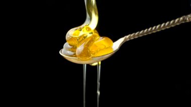 Doğal arı balı kaşığa akıyor ve damlıyor, siyah arka planda makro.