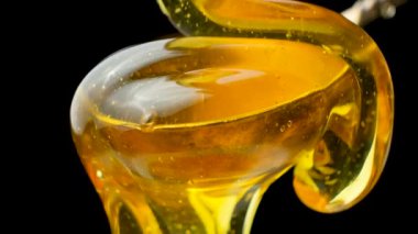 Altın organik bal akışı ve metal kaşıktan damlayan siyah bir kaşık.