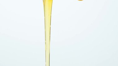 Beyaz zemin üzerinde sıvı doğal bal akışının makro yavaş çekimi