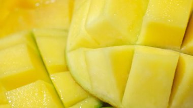 Sulu mango yarıları küp kesim desenli sarı arkaplanda yakın çekim rotasyonu