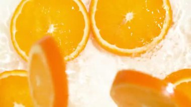 Yukarıdan portakal dilimleri düşerken sinematik su sıçraması.