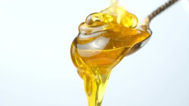Altın organik bal akışı ve metal kaşıktan damlayan beyaz bir kaşık.