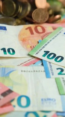 Banknotun arka planına düşen Euro sent paralarının dikey yavaş çekimi