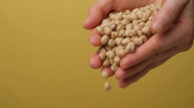 İnsan elleri bir avuç kuru nohutu ağır çekimde dolduruyor..