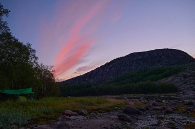 Kuzey Denizi 'nde gün doğumu. Adalar. Pembe bulutlar tepenin üstünde asılı. Yaz. Rusya.