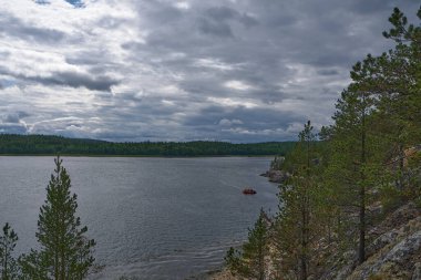 Uçurumdan kayalık sahile bak. Şişme tekne kıyıda yüzüyor. Kasvetli, bulutlu bir gün.