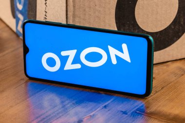 Ekran akıllı telefonunda Ozon logosu var. Yakın plan. Özon, Rusya 'daki ilk e-ticaret şirketlerinden biri. Paketin arka planında akıllı telefon.