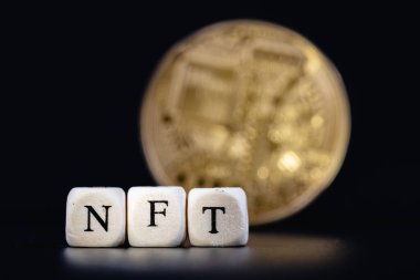 NFT (finanse edilemeyen sembol), eşsiz bir dijital varlık ile bağlantı kurmak için blockchain teknolojisini kullanan özel bir kripto jetonudur. NFT sözcüğü altın kripto sikkenin üzerinde harfler olan küplerden oluşur.