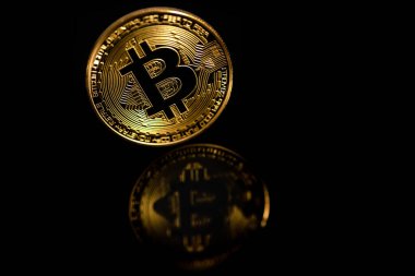 Siyah arka planda yansıması olan yakın plan altın bitcoin. Bitcoin aynaya yansıyor.