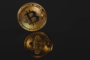 Siyah arka planda yansıması olan yakın plan altın bitcoin. Bitcoin aynaya yansıyor.