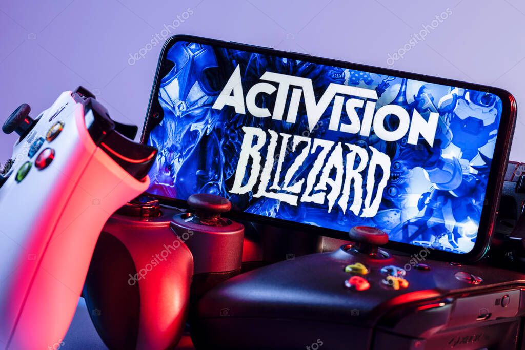 Kazan, Russia - August 7, 2021:  Activision Blizzard, Inc. is an American video game holding company. A smartphone with the Activision Blizzard logo on the screen on the pile of the gamepads.