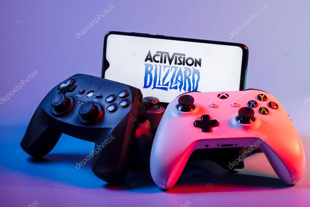 Kazan, Russia - August 7, 2021:  Activision Blizzard, Inc. is an American video game holding company. A smartphone with the Activision Blizzard logo on the screen on the pile of the gamepads.
