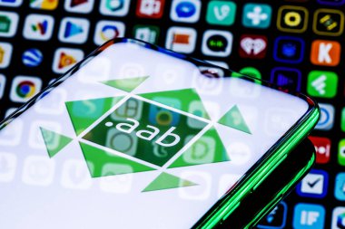 Kazan, Rusya - 15 Ağustos 2021: Android App Bundle (AAB) Android için yeni bir uygulama dağıtım formatıdır. Üzerinde AAB logosu olan bir akıllı telefon. Arkaplanda birçok uygulama simgesi.