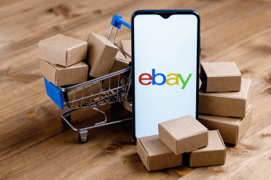 Kazan, Rusya - Sep 25, 2021: eBay online alışveriş, açık artırma ve pazar hizmetleri sunan bir e-ticaret şirketidir. Ekranında eBay logosu olan akıllı telefon, alışveriş arabası ve paketler..