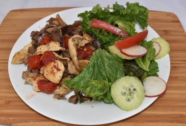 Bir tabak tavuk fajita ve ahşap masada salata.