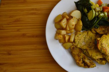 Ahşap bir masada sebzeli tavuk ve köri yemeği manzarası.