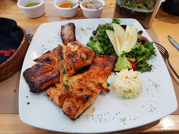 Un plat appelé Salmon Zarandeado, servi avec du riz et de la salade sur une assiette blanche — Photo