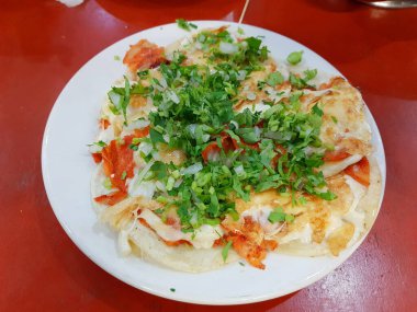 Yanında kişniş ve soğan eşliğinde peynirli tacos al pastor.