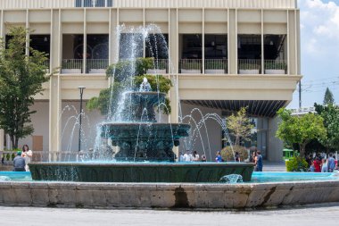 Zapopan, Mexico - August 10 2025: Urban fountain in Zapopan spraying water in tiers with contemporary architecture in the background